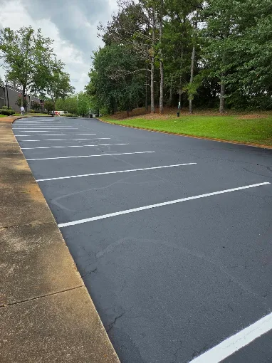 Resurfaced asphalt parking lot with crisp white parking stall lines beside a curb